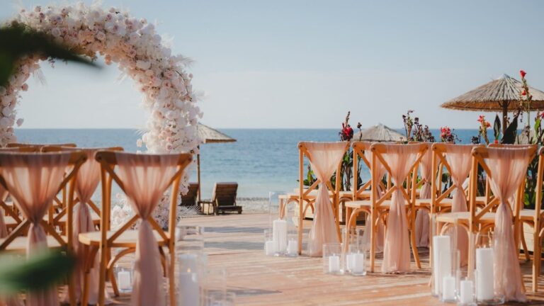 Blush floral arch and peach-draped chairs on the beach, Sense by the Sea, Paphos Weddings Made Easy
