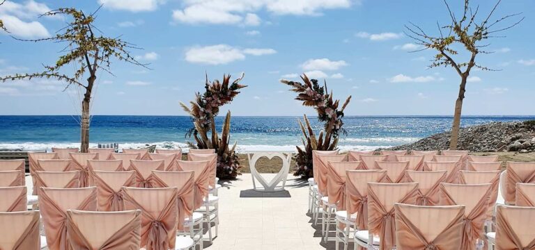 Blush-draped ceremony chairs facing the sea, Coral Residences, Paphos Weddings Made Easy
