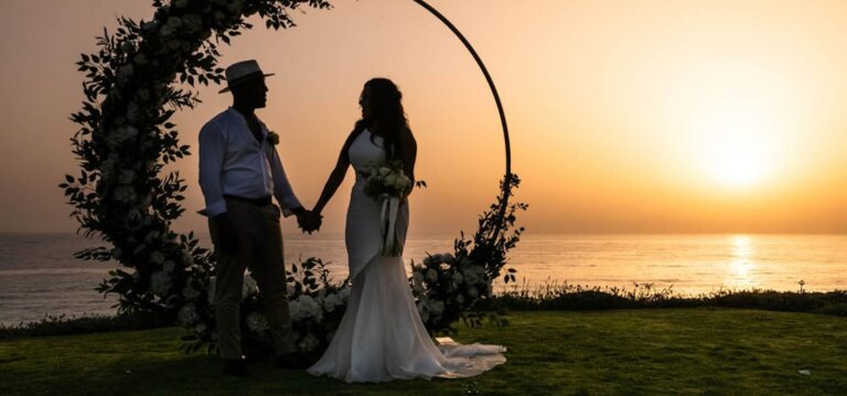 Couple holding hands before a floral ring at sunset, Alassos, Paphos Weddings Made Easy