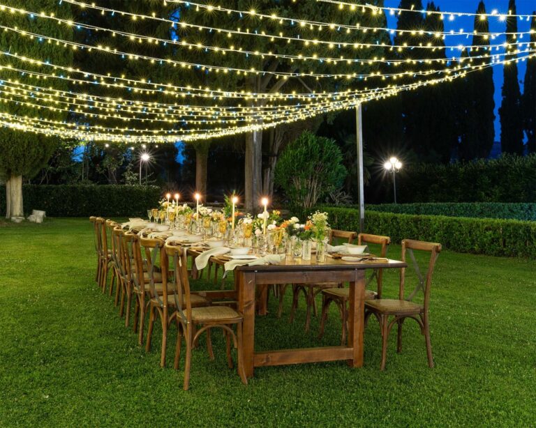 A long banquet table under festoon lights in the park, Parco dei Cavalieri
