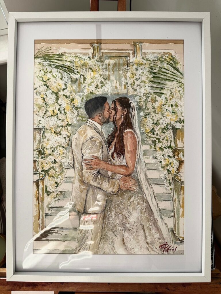 Framed watercolour of a couple kissing before a wall of white flowers, Patrick Heisel Watercolours