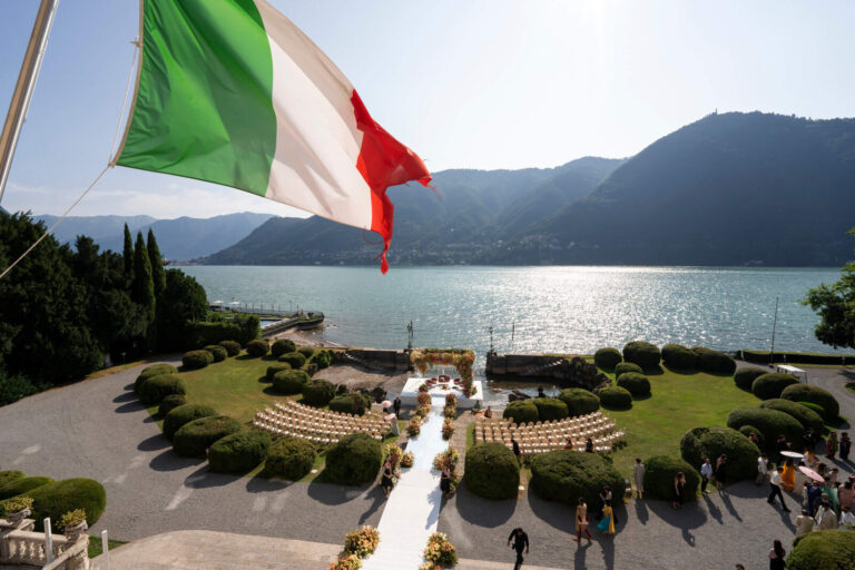 Aerial view of a lakeside ceremony layout with an aisle and seating arranged in a garden, Patrizia Cilli Events Italy