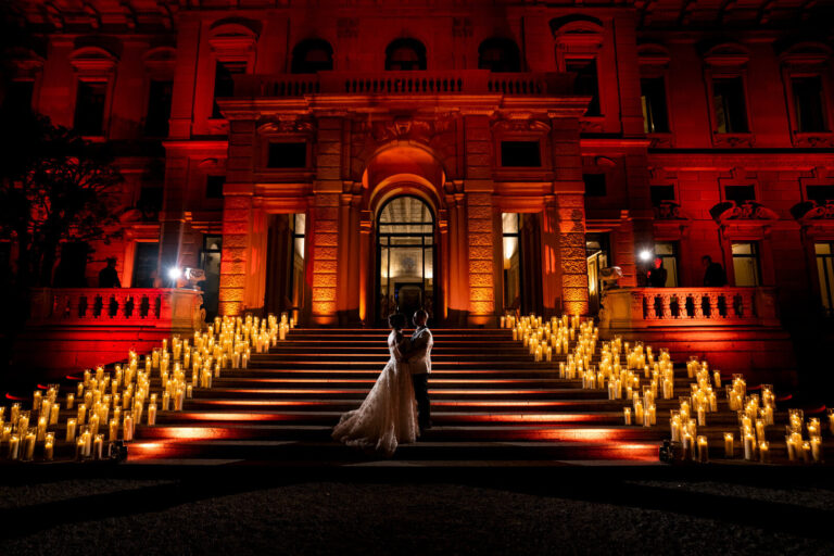 Couple on a candlelit staircase below a red-lit villa facade, Patrizia Cilli Events Italy
