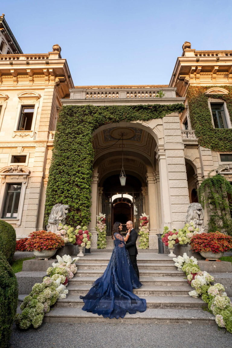 Couple in a blue gown on an ivy-framed villa entrance, steps lined with white hydrangeas, Patrizia Cilli Events Italy