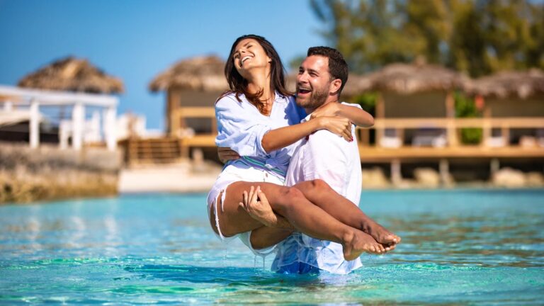 A couple in the turquoise water by the cabanas, Pearl Island Bahamas