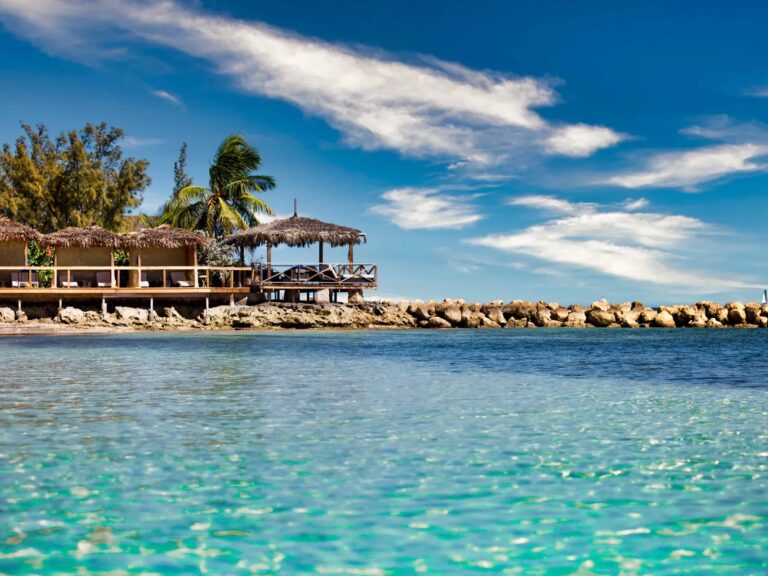 Ocean-view cabanas with thatched roofs, seen from the water, Pearl Island Bahamas