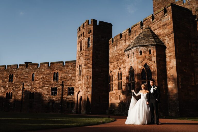 A couple before the red sandstone towers of the castle at golden hour, Peckforton Castle