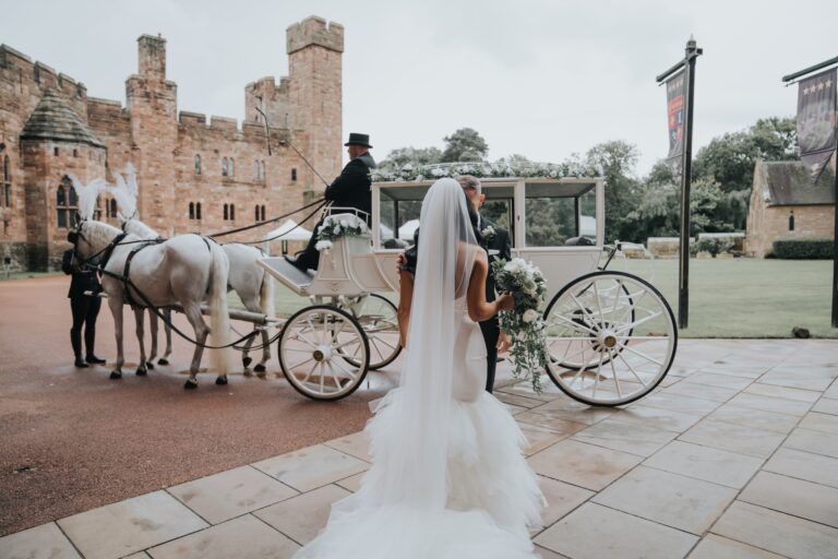 A bride steps toward a white horse-drawn carriage before the castle, Peckforton Castle