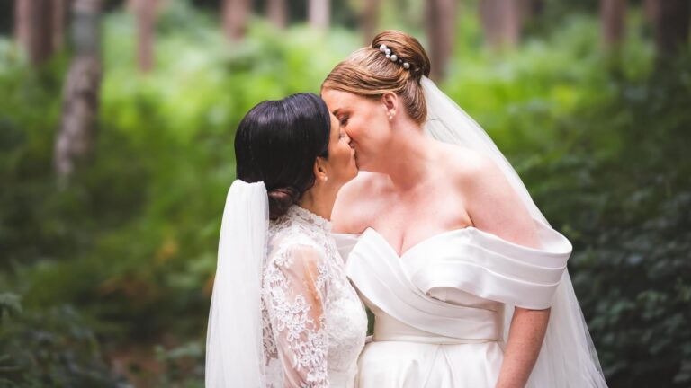 Two brides share a kiss in the castle's woodland, Peckforton Castle