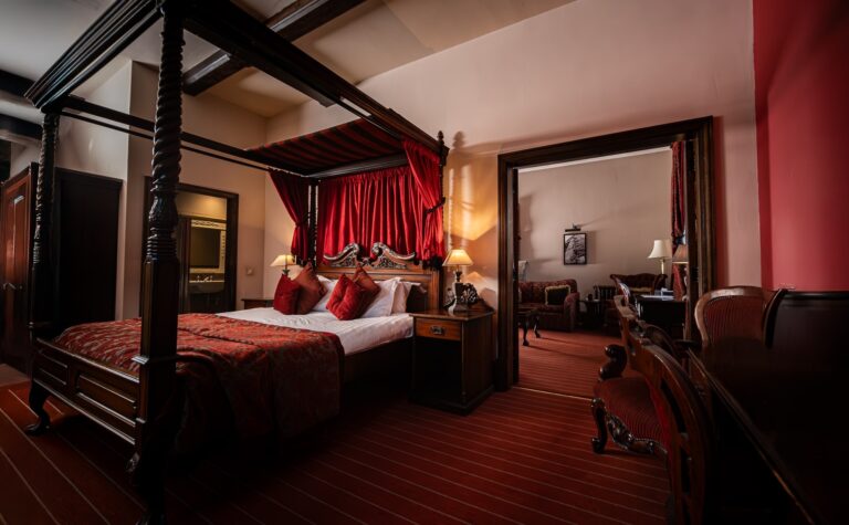 A four-poster suite in rich reds, a carved mahogany bed and heavy drapes, Peckforton Castle
