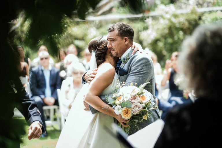 A ceremony embrace, the couple among their guests, Pentillie Castle