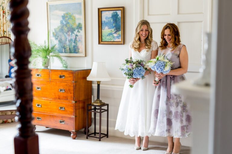 The bride and a bridesmaid by an antique dresser, Pentillie Castle