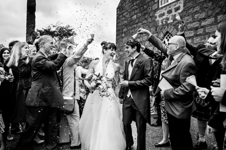 Black and white confetti moment outside a stone building, Petr Pelucha Photography