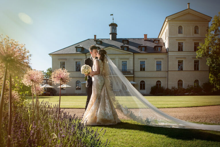 Couple and long veil on the chateau lawn in evening sun, Petr Pelucha Photography