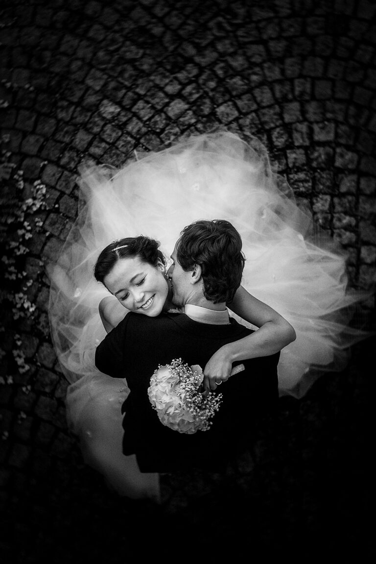 Couple and bouquet seen from above on cobblestones, black and white, Petr Pelucha Photography