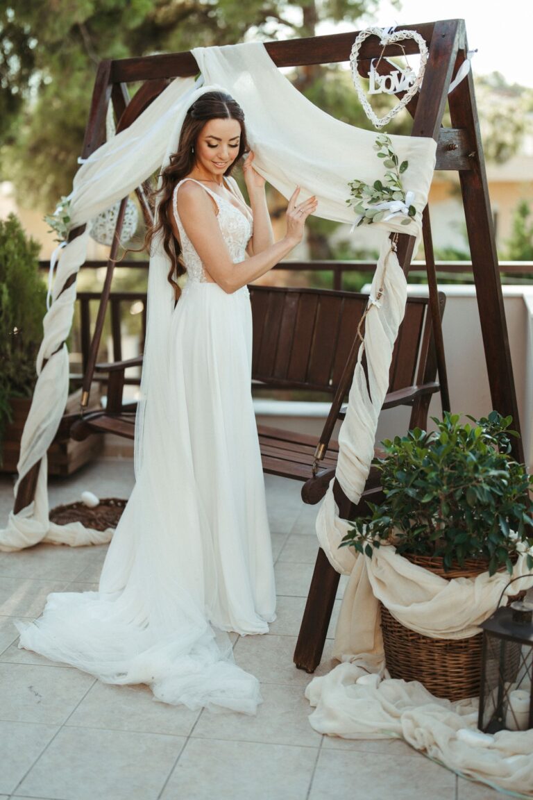 The bride beside a draped wooden swing before the ceremony, Photomad