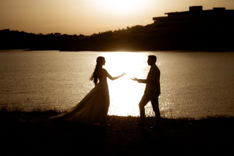 A couple in silhouette at sunset beside the water, Photomad