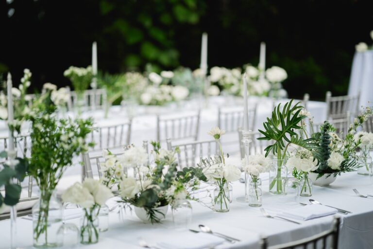 A long reception table laid with white flowers, candles, glass vases and palm leaves at Avani Khao Lak, Phuket Romance