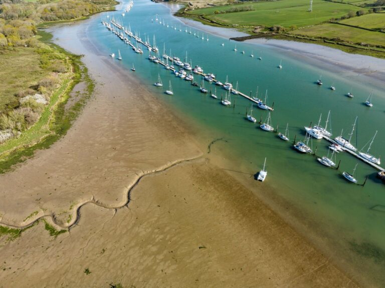 The River Medina from the air at low tide, with yachts on the pontoon moorings and mudflats along the bank, Pinkmead Estate