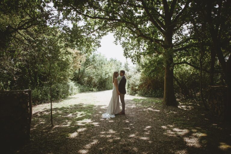 A couple under an arch of oak trees on a shaded woodland path, Pinkmead Estate