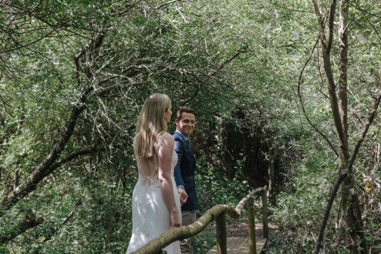 A couple crossing a rustic timber footbridge in the estate woodland, Pinkmead Estate