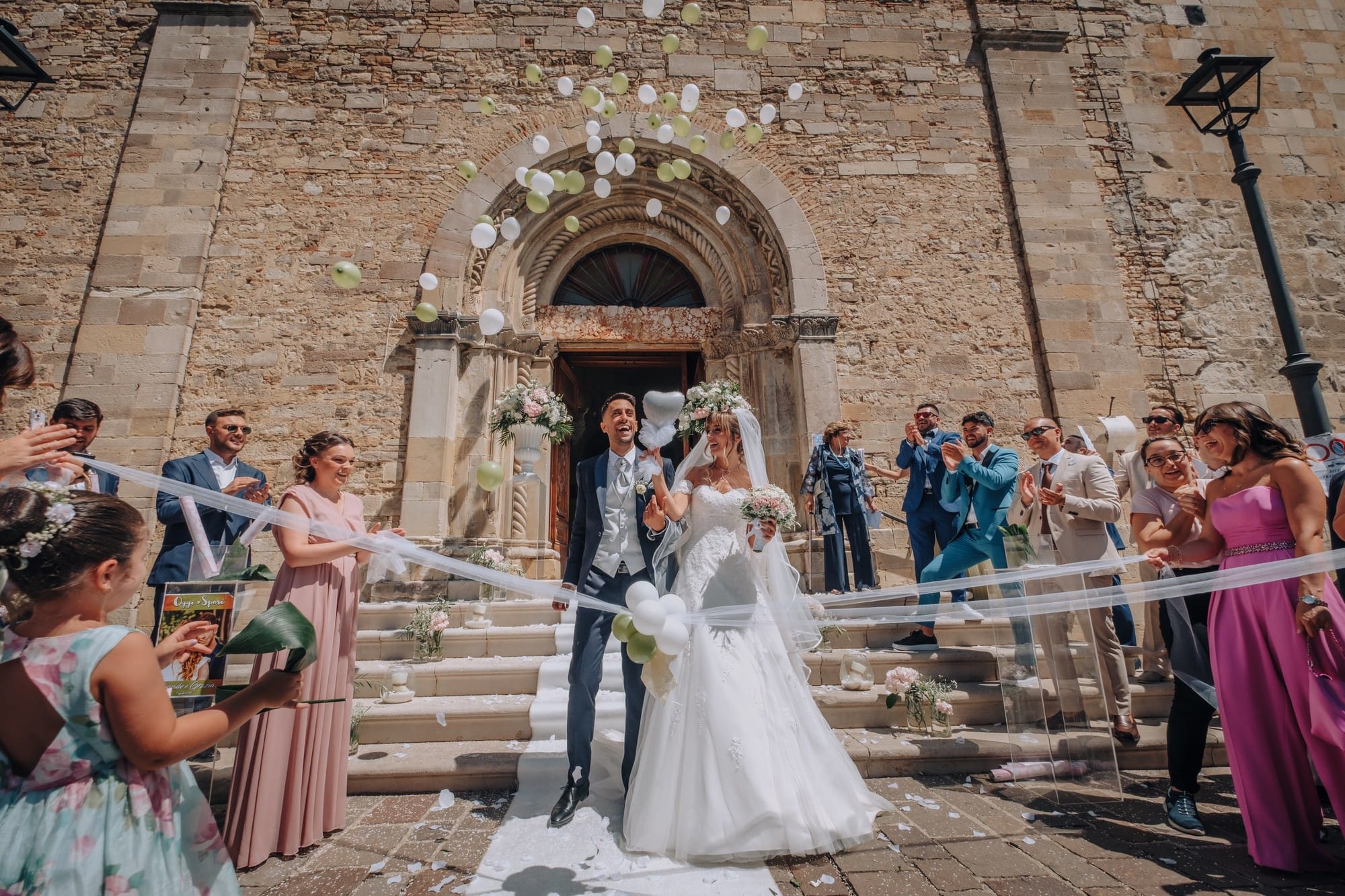 Confetti and ribbons as the couple step out of a stone church, Pino Coduti Photography
