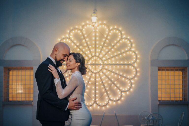 A couple face to face beneath an illuminated rosette of festival lights, Pino Coduti Photography