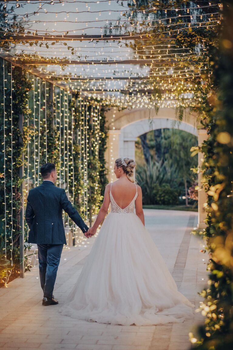 Alessia and Luigi walk hand in hand under hanging lights at Lavinia Bianchi, Trani, Pino Coduti Photography