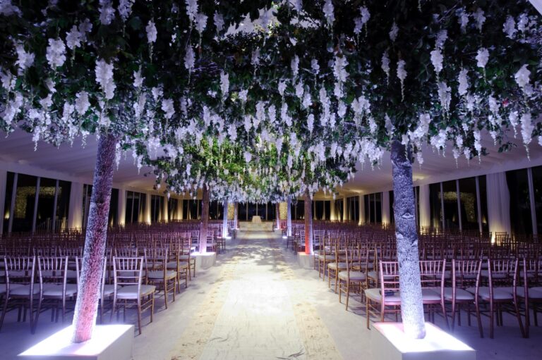 A ceremony aisle beneath hanging wisteria and floral trees, lit from below, Preston Bailey
