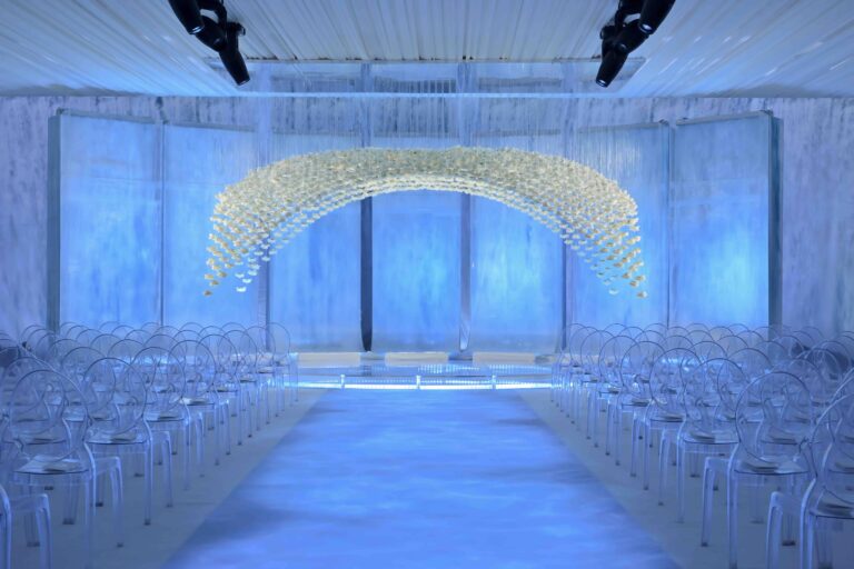 A ceremony set in Las Vegas with an arch of white blooms against softly lit panels, Preston Bailey