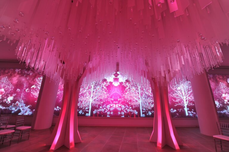 A ceremony beneath a ceiling of pink hanging strands and sculpted floral columns, Preston Bailey