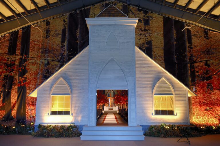 A white chapel built inside a marquee, with autumn foliage behind, Preston Bailey