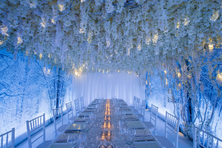 A long dinner table beneath a tunnel of white hanging blossoms, Preston Bailey