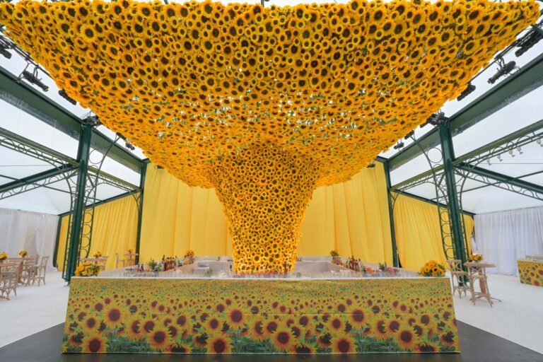 A ceiling and column of sunflowers over a head table in a glasshouse marquee, Preston Bailey