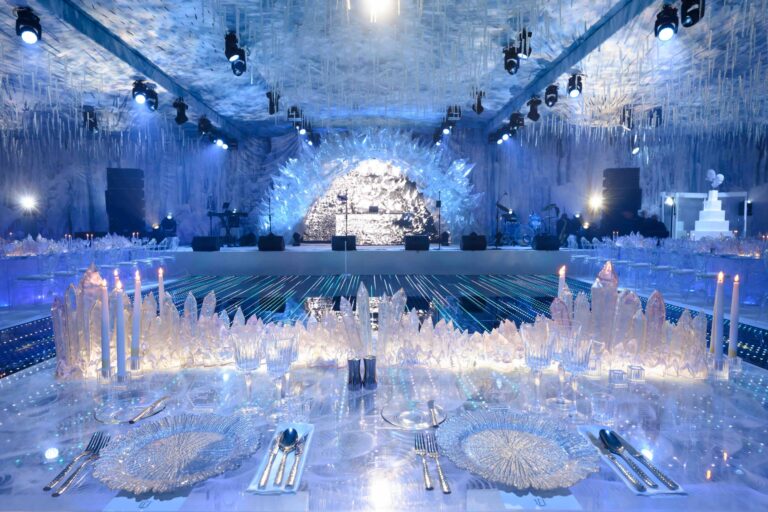 A reception table of crystal and candles before a stage under a lit ceiling of hanging strands, Preston Bailey