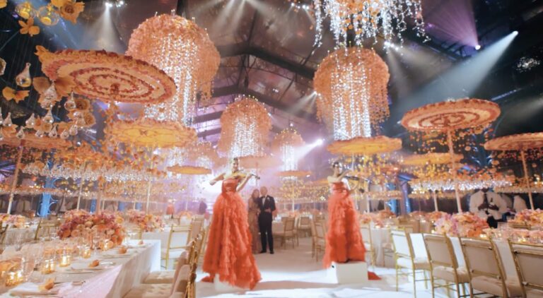 A reception with hanging floral parasols and chandeliers and performers on a lit dance floor, Preston Bailey