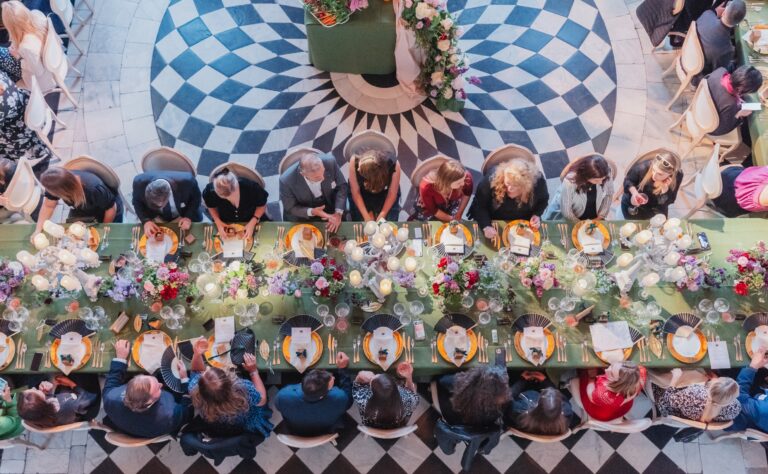 Guests at a long table on the Great Hall floor, seen from above, Queen's House