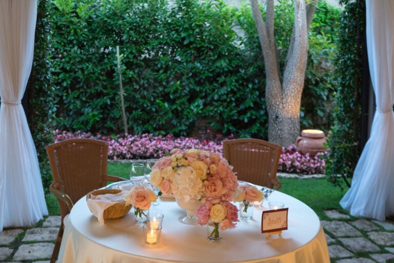 A sweetheart table under the trees, peach and cream blooms, the candles lit, Ramona Avitabile Wedding Planner