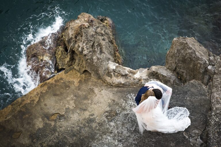 From the cliff above, the dress spread across the rock and the sea turning, Ramona Avitabile Wedding Planner