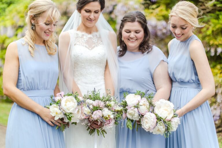 A bride and her three bridesmaids with peony bouquets, beneath a wisteria arch. Photograph by Eddie Judd Photography, Rebecca Mays