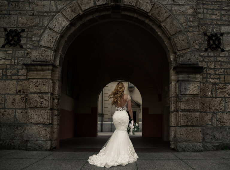 Bride walking through a stone archway, Reflexion Studio