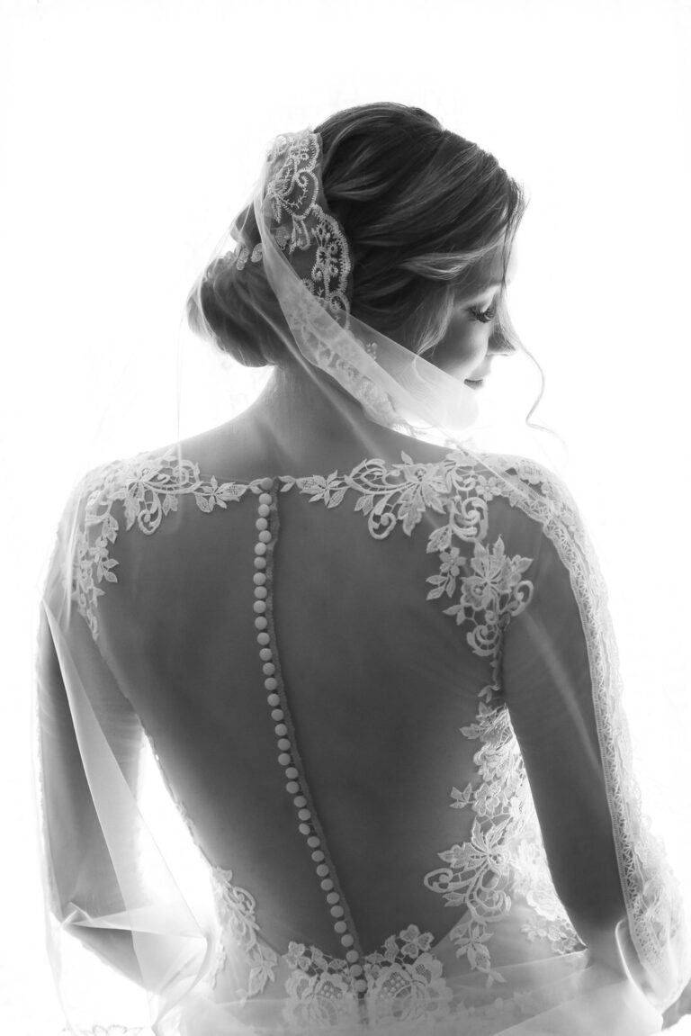 Bride from behind, lace and buttons seen through her veil, Reflexion Studio