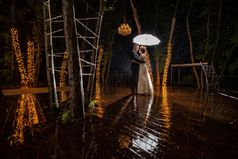 Couple under an umbrella in the rain among festoon lights, Corberon resort, Reflexion Studio