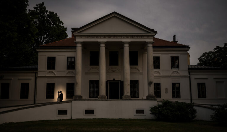 Couple silhouetted at the door of a columned manor house at dusk, Reflexion Studio