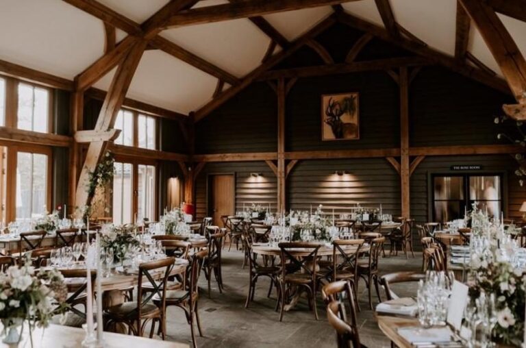 The oak-framed triple-height Great Barn dressed for the wedding feast, long tables under the timber trusses, Retreat East