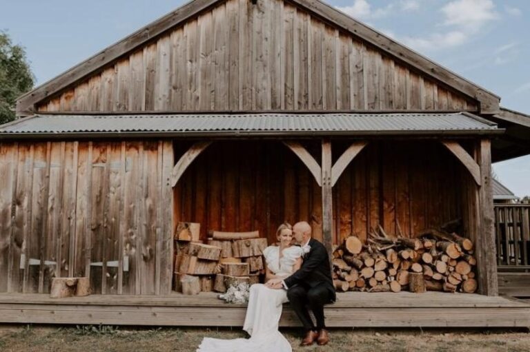A rustic timber barn and log store in the Suffolk countryside, the couple on the veranda, Retreat East