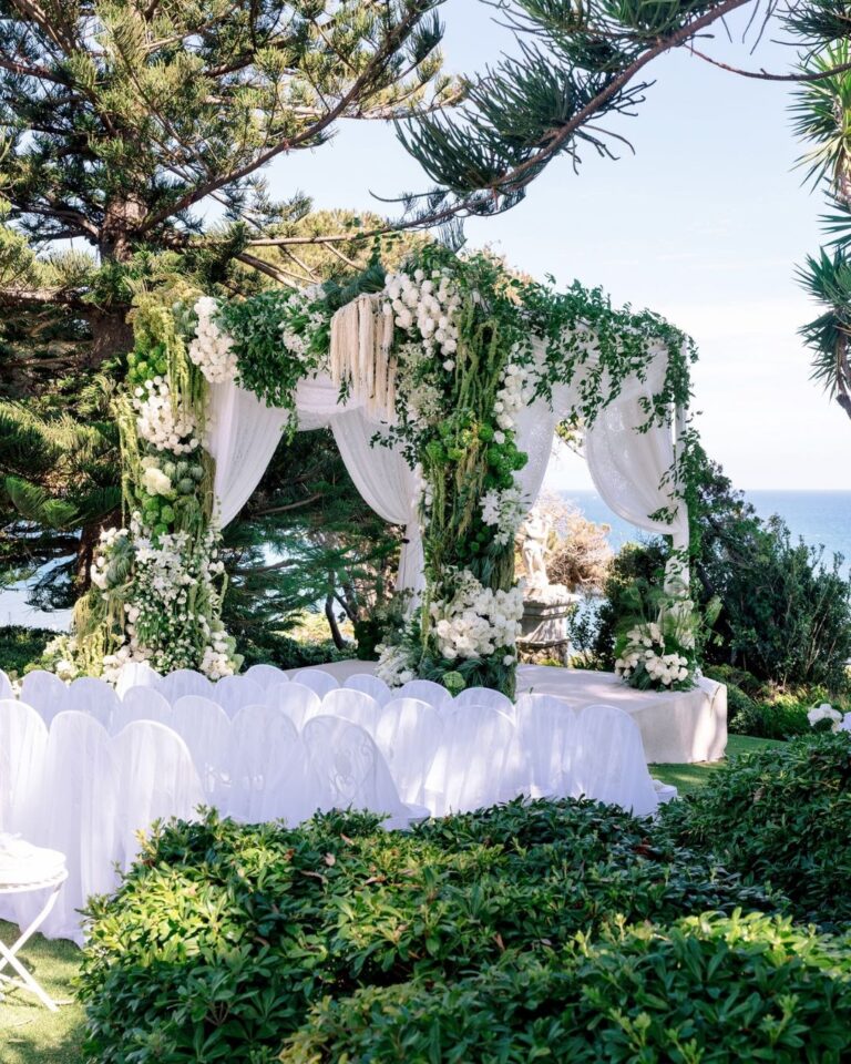 Draped and flower-covered ceremony arch beside the sea, Malibu, Revelry Event Designers