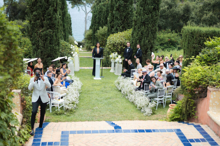 A garden ceremony with guests seated along a flower-lined aisle, Rocabella