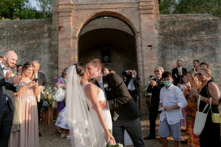 Beatrice and Gennaro kissing beneath a brick archway as guests gather, Castello San Basilio, Rocco Daniele Photography