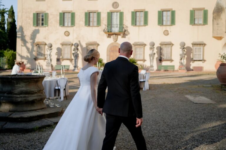Irene and Fabio walking across a villa courtyard at an intimate Tuscan wedding, Rocco Daniele Photography